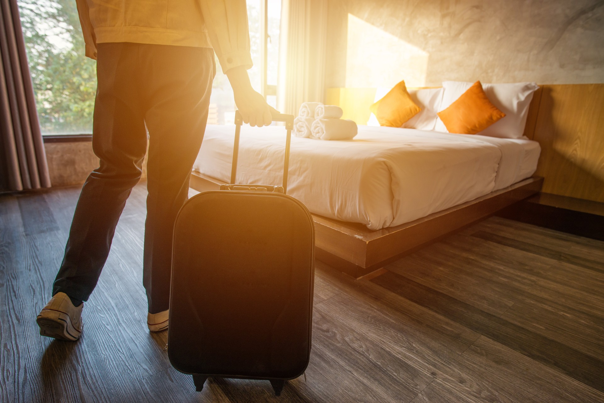 Cropped shot of tourist woman pulling her luggage to her hotel bedroom after check-in.